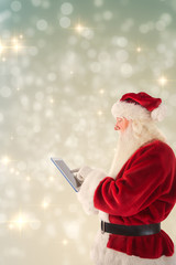 Wall Mural - Santa uses a tablet PC against light design shimmering on silver