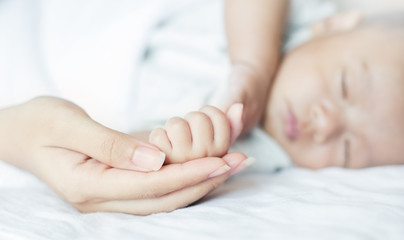 Wall Mural - Asian parent hands holding newborn baby fingers, Close up mother’s hand holding their new born baby. Love family healthcare and medical concept