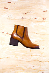 Women's brown leather boots on a white decorative plaster with yellow and brown elements.