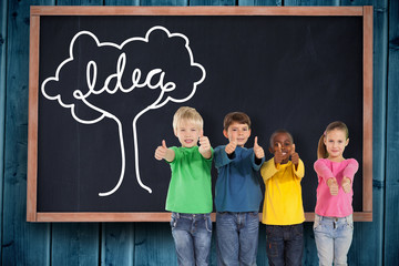 Leinwandbilder - Cute kids showing thumbs up against blackboard on wooden board