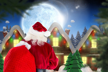 Wall Mural - Santa claus carrying sack against quaint town with bright moon