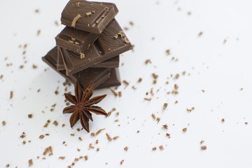 pyramid of chocolate pieces and star anise on white background in centre of picture, sprinkled with chocolate chips, horizontally