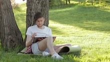 A Young Guy Reading A Book Under A Tree In The Nature