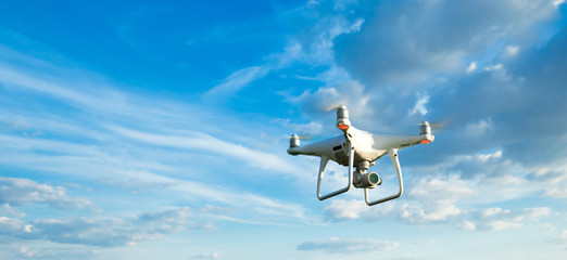 drone flying overhead in cloudy blue sky