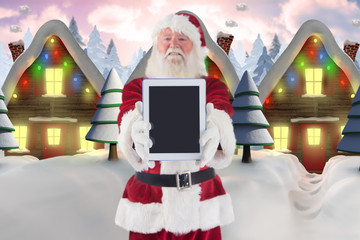 Wall Mural - Santa presents a tablet PC against row of snow covered houses