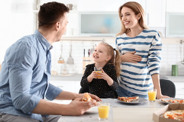 Canvas Print - Pregnant woman and her family eating pizza in kitchen