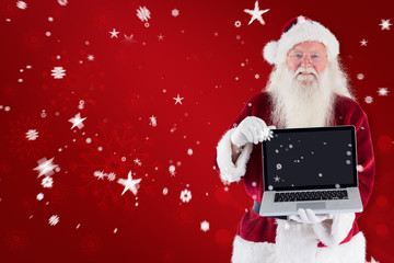 Wall Mural - Santa Claus presents a laptop against red snowflake background