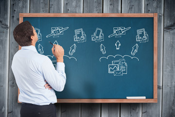 Leinwandbilder - Thinking businessman holding pen against blackboard with technology doodles
