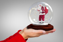 Composite Image Of Hand Holding Santa Snow Globe Against Grey Vignette