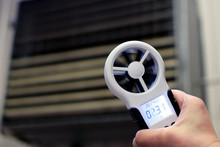 Hand-held Anemometer Measuring Air Flowing Of Ventilation Louvres Of The Industrial Ventilation Unit.