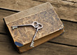 Vintage keys lying on shabby battered old book lying on the wood bench