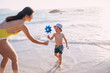 © Criene Images - caucasian mother and sun playing with windmill at the beach