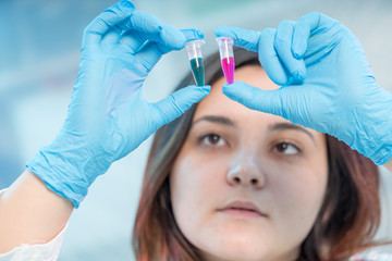 Wall Mural - Female medical worker compares test tubes with biological samples