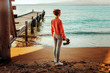 © tinyakov - Girl Traveler With Binoculars In Hand Standing By The Sea Near Pier And Enjoying View Of Nature, Rear View