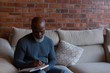 © Wavebreak Media - Senior man writing on diary while sitting on sofa at home
