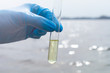 © SecondSide - Hand in glove collects water in a test tube. Concept - water purity analysis, ecology. Water testing for infections