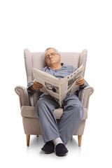 Wall Mural - Mature man with a newspaper sleeping in an armchair