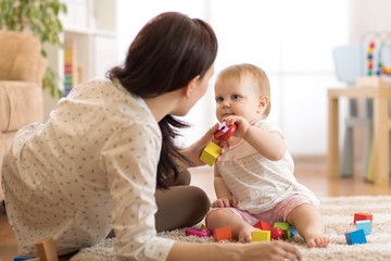 cute baby girl playing with educational toys in nursery. child having fun with colorful different to
