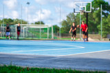 Fototapeta Nowy Jork - Abstract, blurry background of boys playing basketball in outdoor basketball court in park