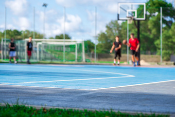 Abstract, blurry background of boys playing basketball in outdoor basketball court in park