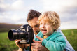 © Halfpoint - A father and his toddler son with a camera outside in spring nature.