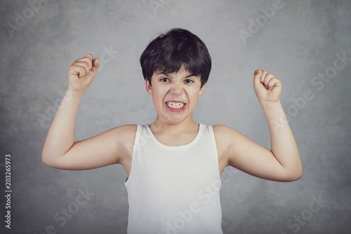 niño fuerte que enseña sus músculos sobre fondo gris Poster