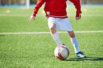 Wall Mural - Foot of child football player and ball