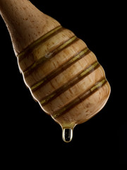 Wall Mural - honey stick with flowing honey isolated on black.