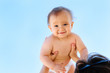 © AMR Studio - Smiling baby in hands of mother against the sky. Portrait of a toddler boy in white diaper in light blue sky. Happy childhood concept