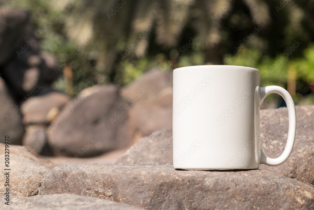 White blank coffee mug mock up, close-up of mug outside in the sunshine on  some