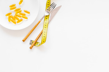 Dietary supplement for well-being. Fish oil or omega-3 capsules on plate near measuring tape on white background top view copy space