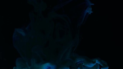 This is a creative artistic macro video of colorful blue abstract shape dropping into black water