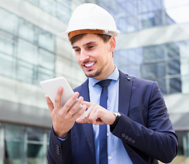 Smiling man working outdoors at modern touchpad