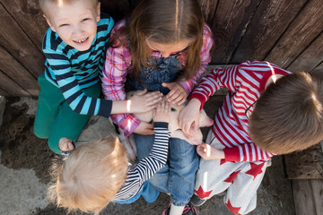 Wall Mural - White pig with black spots of breed pietren sits on hand's farmer's daughter. Children play with newborn piglet in farmyard yard. Preschoolers love to spend vacations in countryside. Selective focus