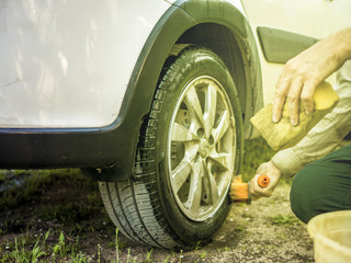 close up hand cleaning washing car wheel on a sunny day outside