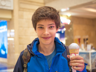 young smiling teenage boy holding and eating ice cream