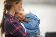 © Erickson Stock - Smiling little girl snuggles happily in her mother's arms.