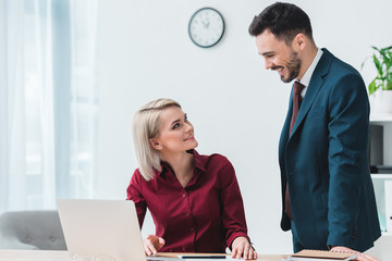 young business colleagues smiling each other while working together in office