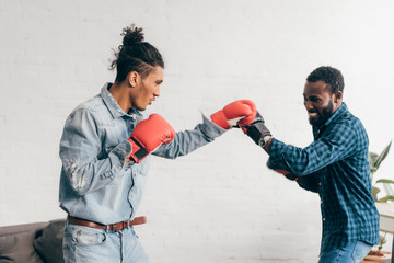 Wall Mural - smiling multicultural male friends doing sparring in boxing gloves