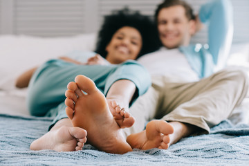 Close-up view of feet of multiracial couple staying in bed