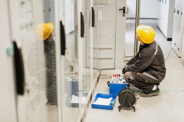 Wall Mural - electrician engineer tests system with relay test set equipment