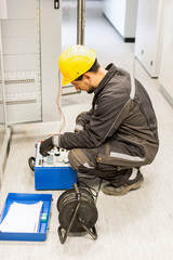 Wall Mural - electrician engineer tests system with relay test set equipment