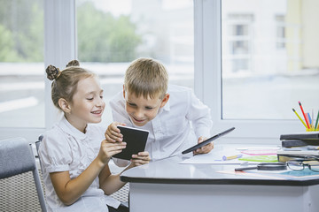 Beautiful children are students together in a classroom at the school receive education with tablets happy