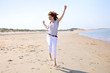 Hübsche rothaarige Frau läuft hüpfend über an einem Strand 