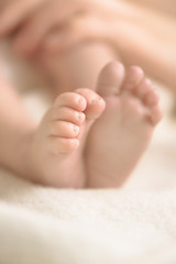 Wall Mural - newborn baby feet on creamy blanket. mom and her child. maternity, family, birth concept. copy space