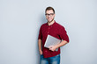 © deagreez - Portrait of smart clever qualified promising it-specialist software developer dressed in red checkered casual shirt, jeans, holding closed netbook in hands, isolated on gray background
