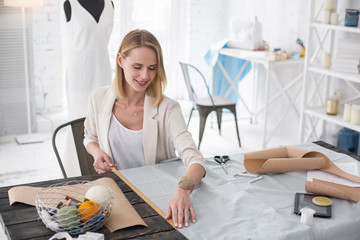 Wall Mural - Fashion career. Top view of exuberant female dressmaker working with fabric and employing meter