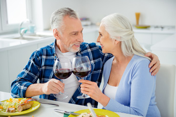 Sticker - Lovely cheerful attractive sweet stylish couple having fun, date enjoying time together indoor, in dining room, looking at each other, clinking glasses with alcohol, holding red wine in hands