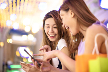 Wall Mural - happy girls using smart phone in the shopping mall