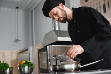 Canvas Print - side view of handsome chef cooking with frying pan at restaurant kitchen